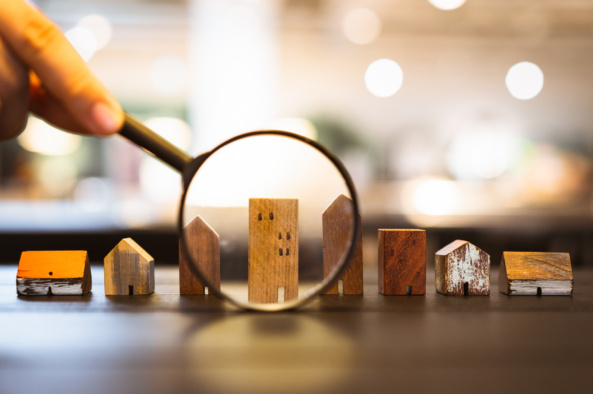 Hand holding magnifying glass and looking at house model, house Hand holding magnifying glass and looking at house model, house selection, real estate concept.